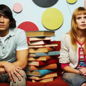 Young Couple Sitting with a Pile of Books