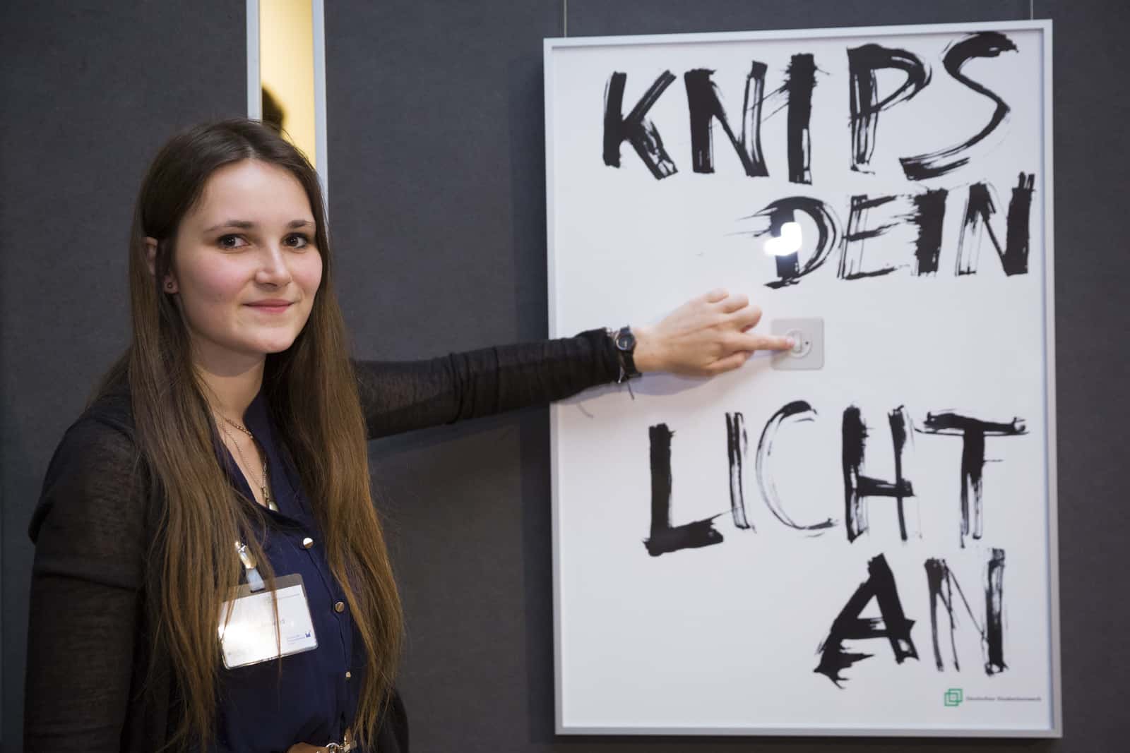 Preisträgerin Alina Mirwald vor ihrem Siegerplakat "Knips dein Licht an". Foto: Kay Herschelmann