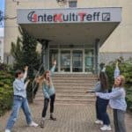 Studierende zeigen auf den Eingang des InterKultiTreff
